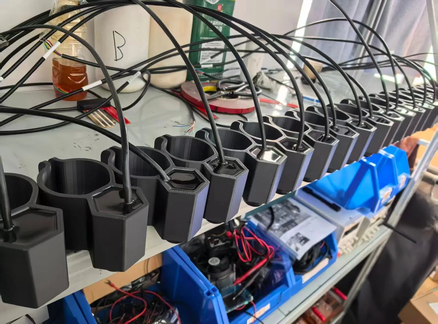 A row of custom seawater lux sensors in production, each with a moulded dark housing and a potted cable exit