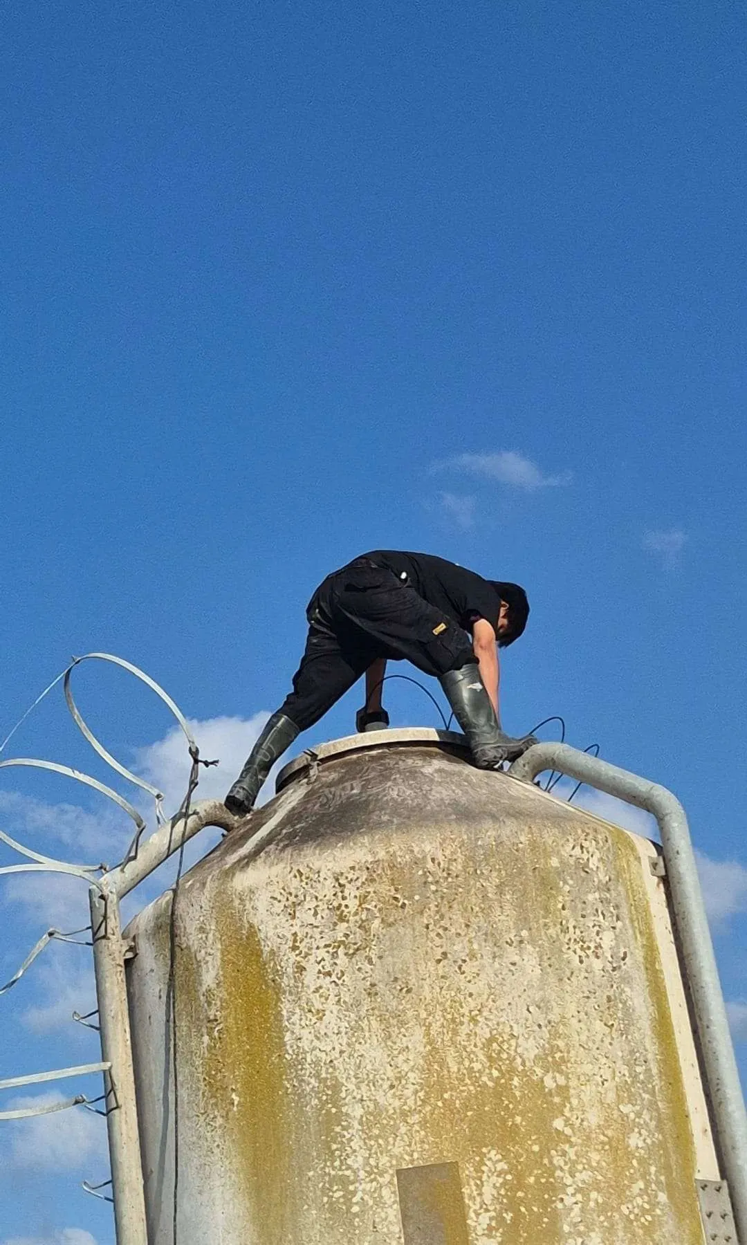 Vista desde el suelo de la altura completa del silo de alimento exterior, con un técnico trabajando en la escotilla superior