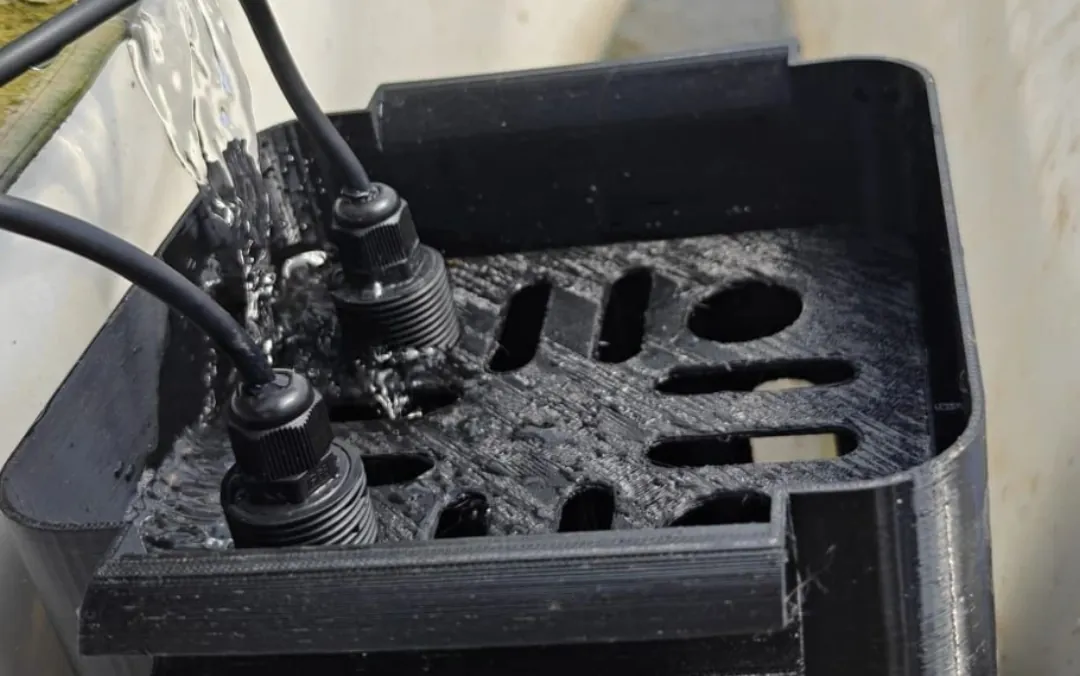 EC and pH probes held in a black 3D-printed housing in a substrate drainage channel, with runoff water pouring over them